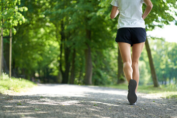 Unrecognizable woman running in the park during summer