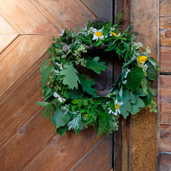 A wreath of flowers, herbs and twigs on the wooden handle of the sauna at the summer solstice