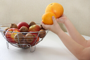 A bowl of fruit. The child takes fruit from a vase and different fruits