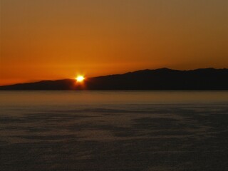 Sonnenuntergang über dem Meer mit Felsen und Sonne in orange