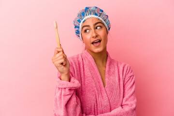 Young caucasian woman holding a toothbrush isolated on pink background