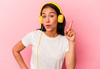 Young Venezuelan woman listening to music isolated on pink background having an idea, inspiration concept.