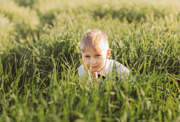 Little boy plays in the grass in nature in summer