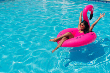 Cheerful young sexy black girl wearing fuchsia swimsuit having fun at hotel outdoor pool in fuchsia...