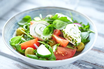 Summer Salad with Cream Cheese, green Olives, Tomatoes and fresh Basil. Bright wooden background. Close up. 