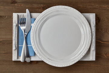 White handmade plate and cutlery on a dark wooden table
