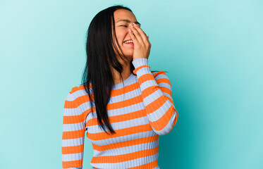 Young Venezuelan woman isolated on blue background laughing happy, carefree, natural emotion.