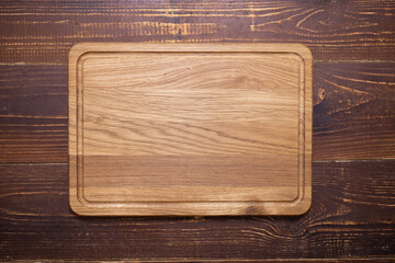 Rectangular empty cutting board  on a wooden background. Place for your text. The concept of baking, cooking. Horizontal. Copy space. 
