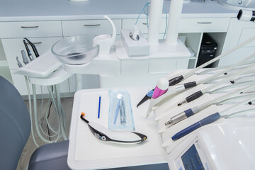 Modern dental office without people. Expensive medical equipment. Selective focus. Light, horizontal. Lamp, tap, chair against the background of a window. Close up. Dentistry Design. New technologies.