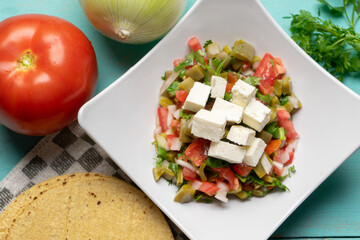 Nopal cactus salad with cheese on turquoise background. Mexican food