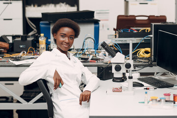 Scientist african american woman engineer working in laboratory with electronic tech instruments and microscope. Research and development of electronic devices by color black woman. - 440658613