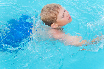 Fototapeta na wymiar Little funny boy in the swimming pool