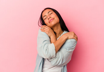 Young Venezuelan woman isolated on pink background hugs, smiling carefree and happy.