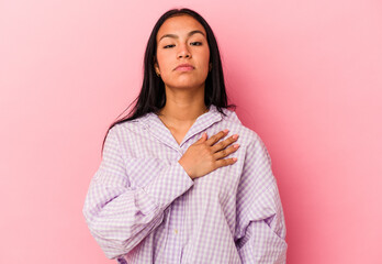Fototapeta premium Young Venezuelan woman isolated on pink background taking an oath, putting hand on chest.