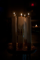 kilka płonących świec w kościele, pośród mroku - obrazy, fototapety, plakaty