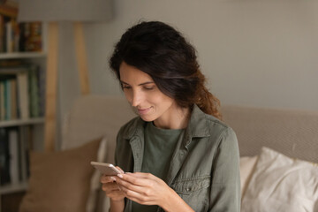 Close up attractive woman holding smartphone, looking at phone screen, scrolling, typing writing message, browsing mobile device apps, shopping or chatting online in social networks with friends