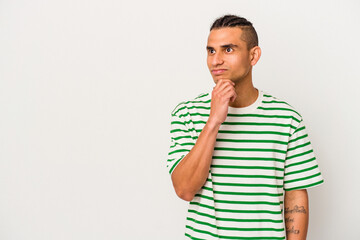 Young venezuelan man isolated on white background looking sideways with doubtful and skeptical expression.