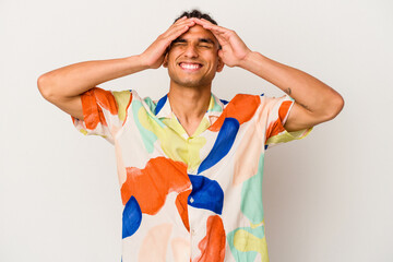 Young venezuelan man isolated on white background laughs joyfully keeping hands on head. Happiness concept.