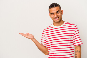 Young venezuelan man isolated on white background showing a copy space on a palm and holding...
