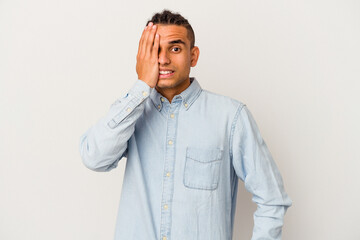 Young venezuelan man isolated on white background having fun covering half of face with palm.