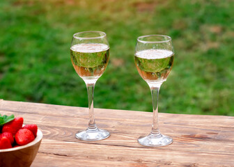 two glasses of champagne on wooden table in the garden