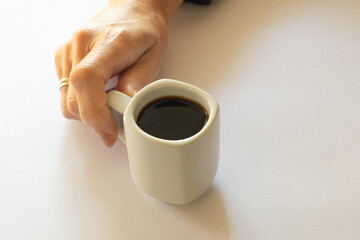 Hand holding a white coffee cup