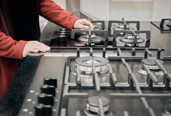 Woman in a store chooses for buy a gas stove. She carefully examines the burners. The concept of buying new gadgets and household devices for the home. Hands close up shot