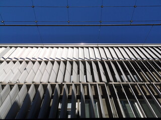 Moderne Fassade mit Lamellen als Sonnenschutz eines Geschäftsgebäude vor blauem Himmel bei...