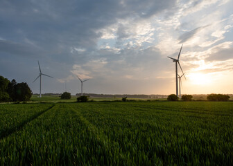 An electricity generating windmills on the green field against cloudy blue sky in England