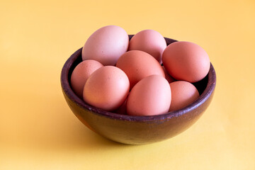 Eggs on a artesanal brown bowl on a yellow background