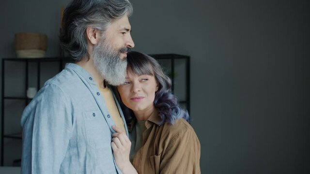 Slow motion portrait of mature man and young woman hugging standing indoors in apartment expressing love and care. Beautiful people and affection concept.