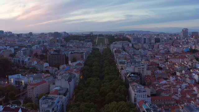 Aerial slow dolly in view of large public park Parque Eduardo VII with lush green vegetation in urban city center of Lisbon, Portugal
