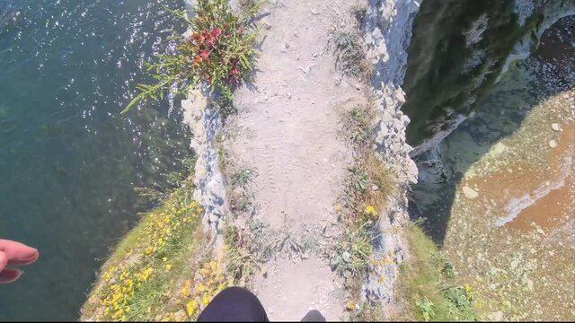 POV dangerous risky walk footpath on very high cliffs of Old Harry rocks in Uk. Ocean below.