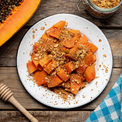 Cutted papaya fruit with granola muesli for breakfast on wooden background