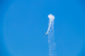 Stund plane doing a loop with smoke in turquoise blue sky.