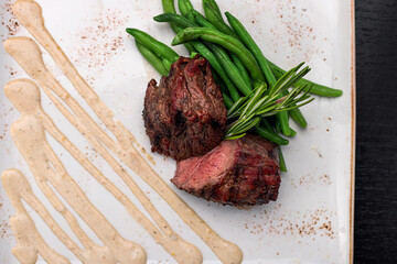 Filet mignon with asparagus on a light plate, on a dark background