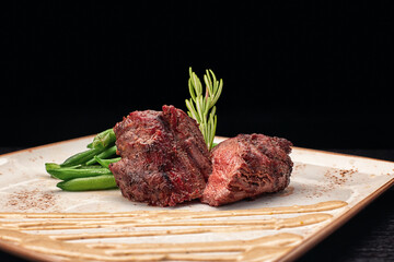 Filet mignon with asparagus on a light plate, on a dark background