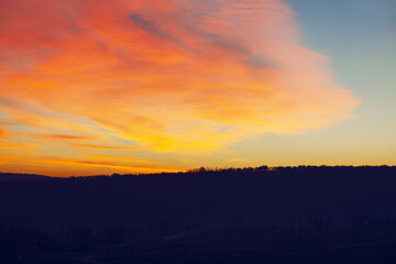 Colorful sunset over the mountain hill . Red beautiful clouds in the evening
