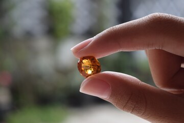 Natural yellow citrine quartz oval in women hand. Isolated on blurred background.