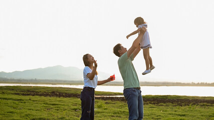 Asian family of father, mother, and two kids having a quality time in meadow. Shot at summer