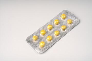 Yellow round tablets in a blister on a white background closeup.
