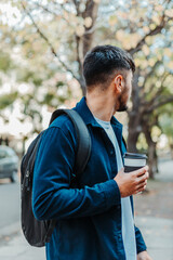 latin man standing with a cup of coffee and a coat