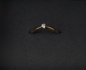 Gold engagement ring with a diamond closeup in a box.