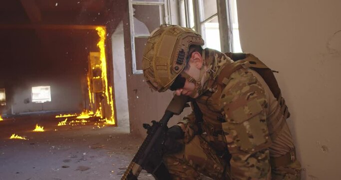 Modern warfare soldier in action near window changing magazine and take cover. Shooting trough a window in urban battlefield.