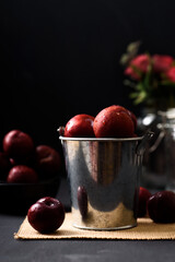 Japanese or Chinese red plum fruit in a bucket on black background