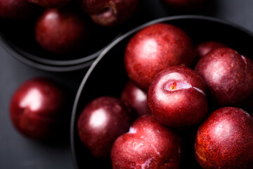 Japanese or Chinese red plum fruit in a bowl on black background, Top view