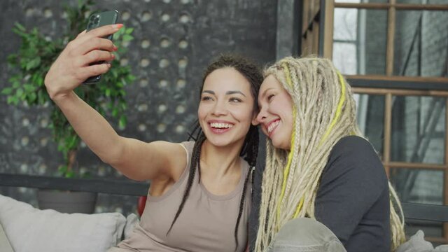 Smiling millennial women making photographs of themselves
