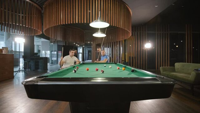 Adult men with disabilities in a wheelchair play billiards in the club