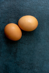 Two brown eggs on textured dark gray slate background.
