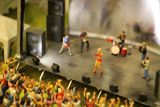 Selective focus shot of a mini toy stage with little figures represented as a band and the crowd